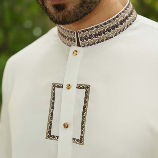 White traditional outfit with intricate collar design against a blurred green background