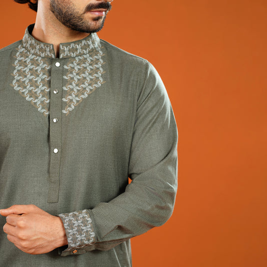 Man wearing a green kurta with intricate white embroidery on an orange background