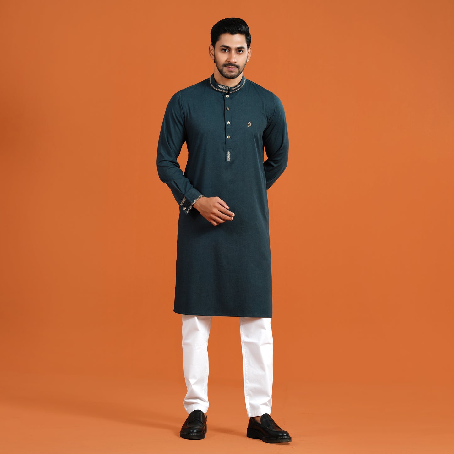 Man wearing a dark green kurta with white pants on an orange background