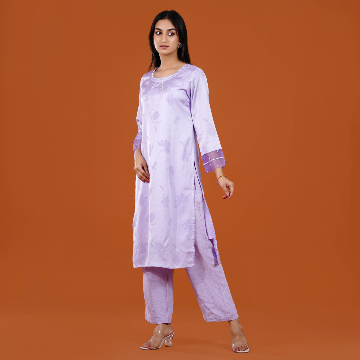 Woman wearing a light purple kurta with pants on an orange background