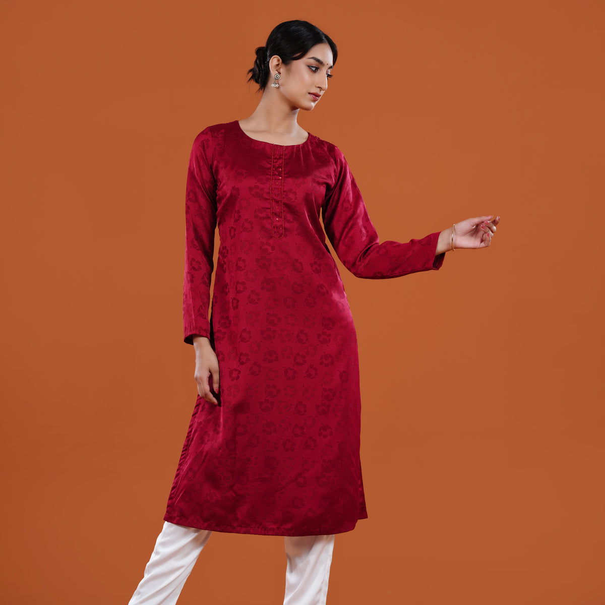 Woman wearing a red kurta with white pants on an orange background