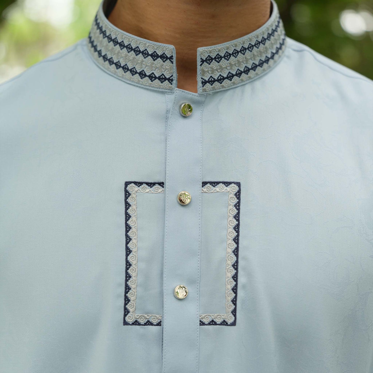 Light blue kurta with embroidered details on a blurred natural background