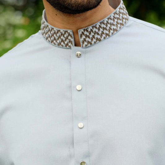 Light blue shirt with patterned collar worn by a person, blurred green background