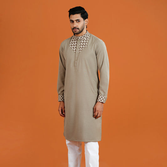 Man wearing a beige kurta with white pants on an orange background
