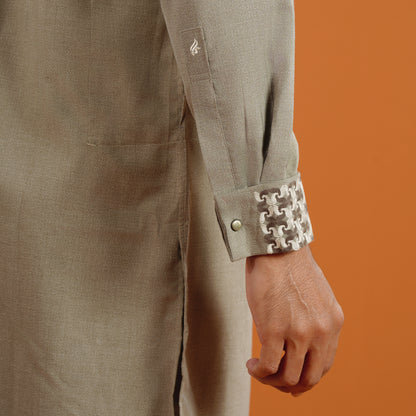 YAMAAN Close-up of a person wearing a green panjabi with a patterned cuff against an orange background