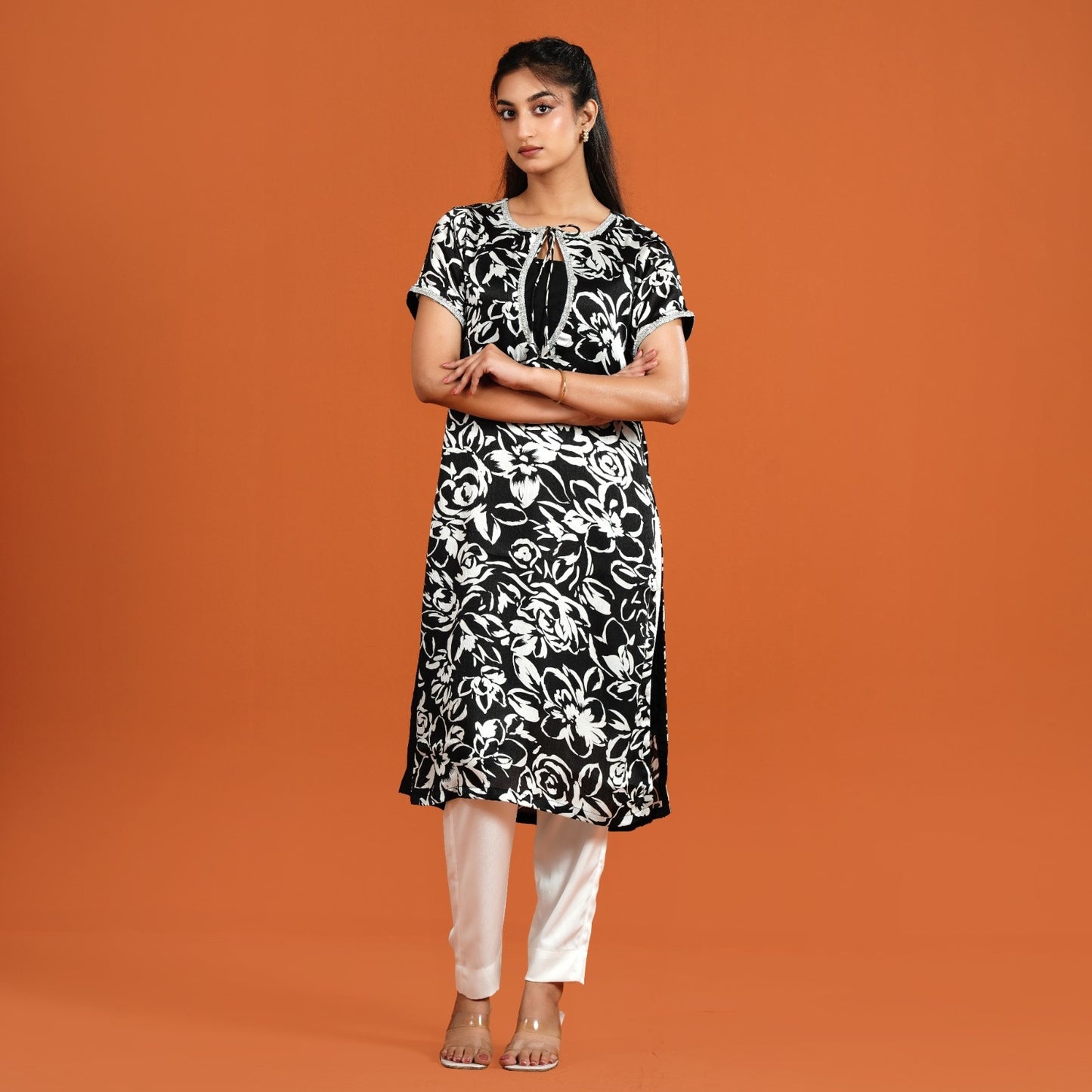 Woman wearing a black and white floral dress against an orange background