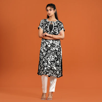 Woman wearing a black and white floral dress against an orange background