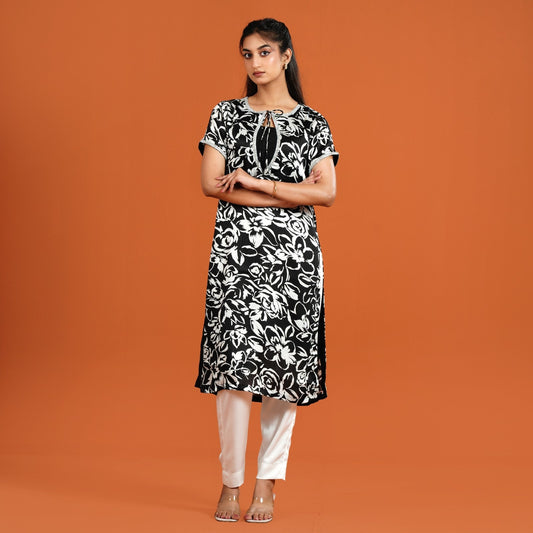 Woman wearing a black and white floral dress against an orange background