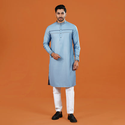 Man wearing a light blue kurta with white pants on an orange background