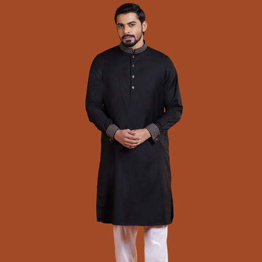 Man wearing a black YAMAAN
 kurta with white pants on an orange background