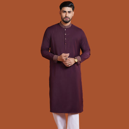 Man wearing a maroon YAMAAN kurta with white pants on an orange background