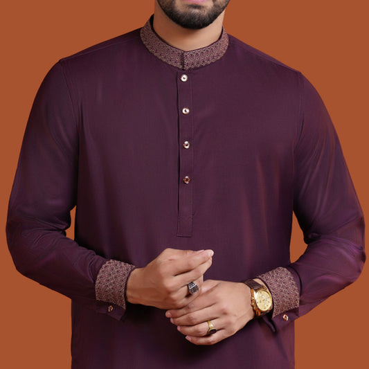 Man wearing a dark maroon YAMAAN traditional outfit with intricate patterns on a brown background