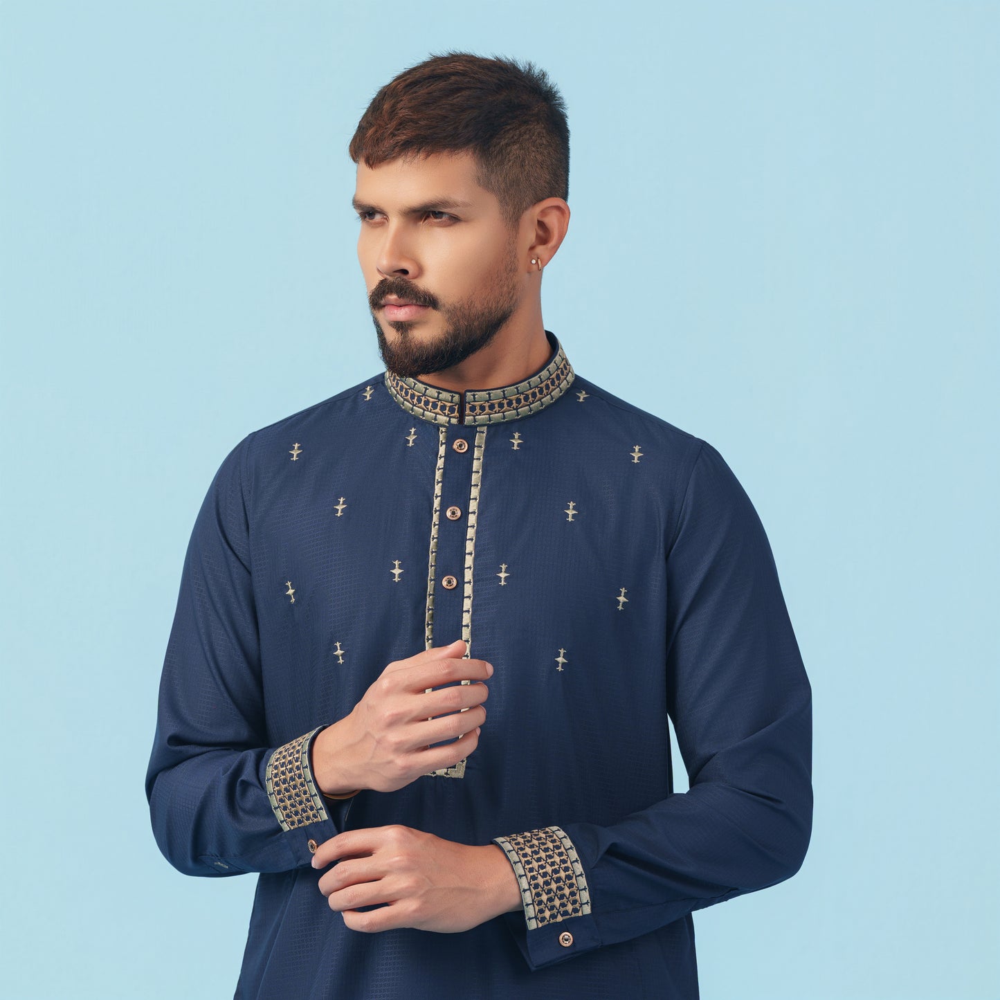 Man wearing a navy blue embroidered YAMAAN panjabi against a light blue background