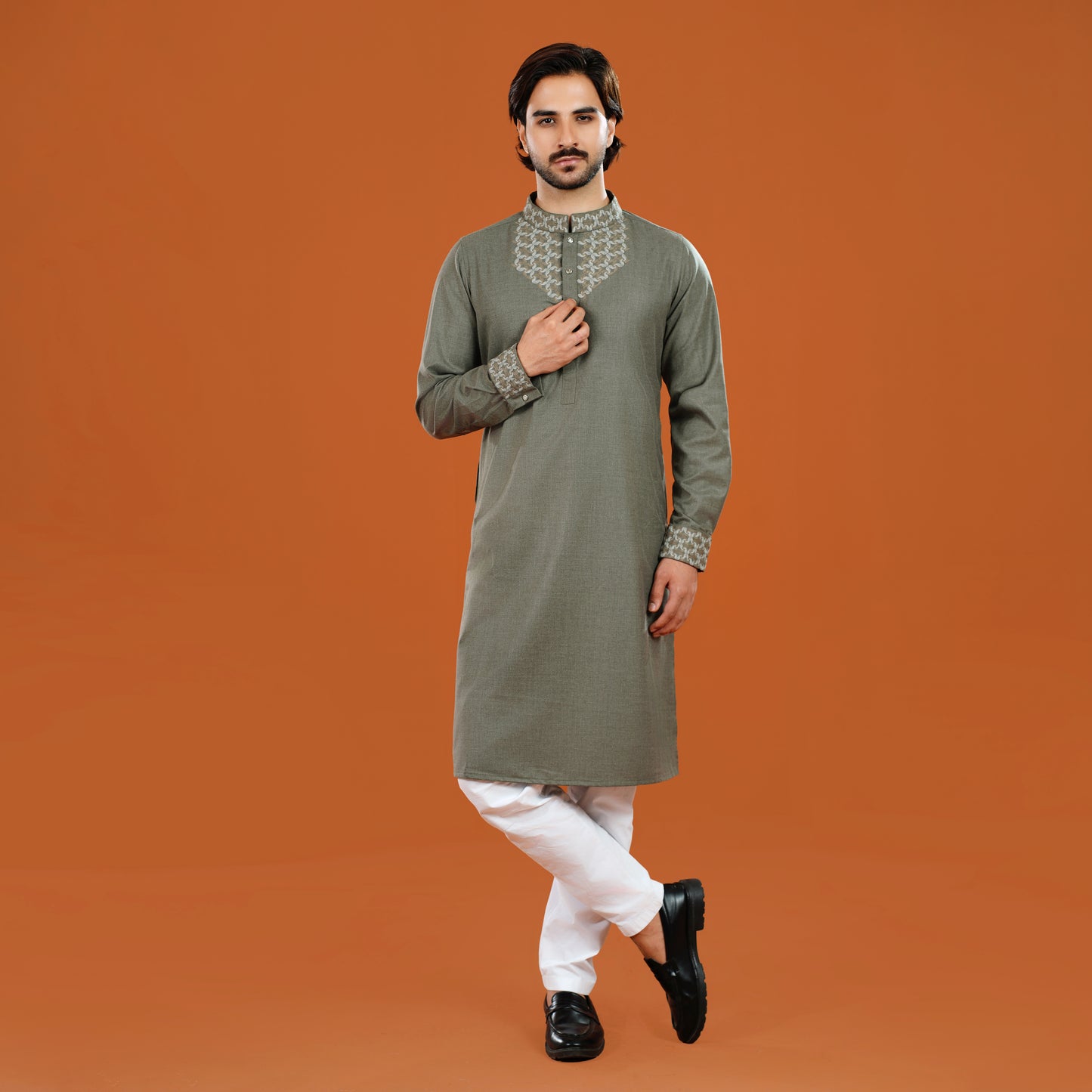 Man wearing a green kurta with white pants on an orange background