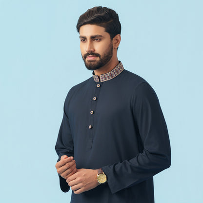 Man wearing a dark blue YAMAAN kurta with a light blue background