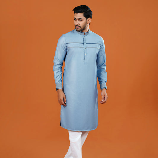 Man wearing a light blue kurta with white pants on an orange background