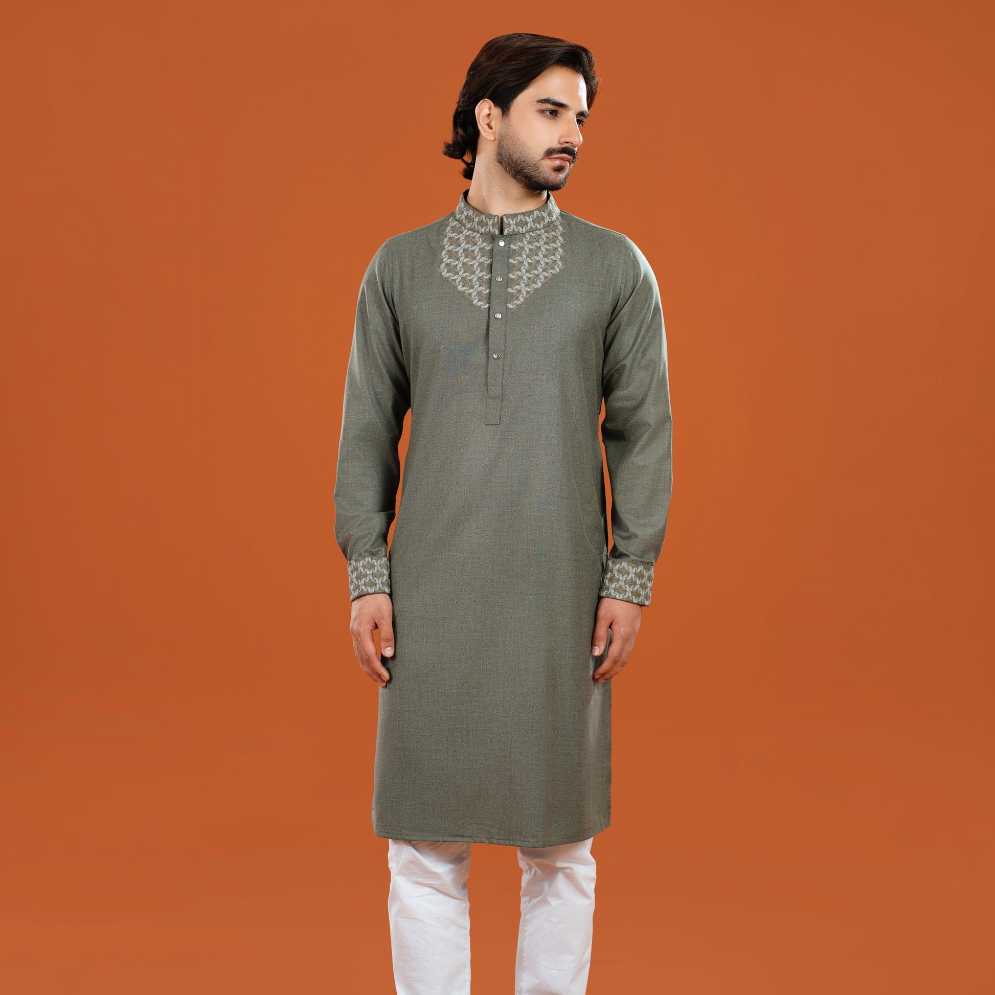 Man wearing a green kurta with white pants on an orange background