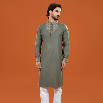 Man wearing a green kurta with white pants on an orange background