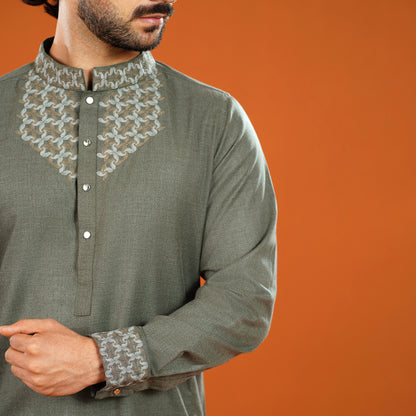 Man wearing a green kurta with intricate white embroidery on an orange background