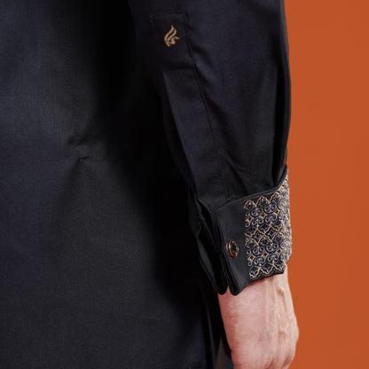Black sleeve with intricate gold embroidery on an orange background