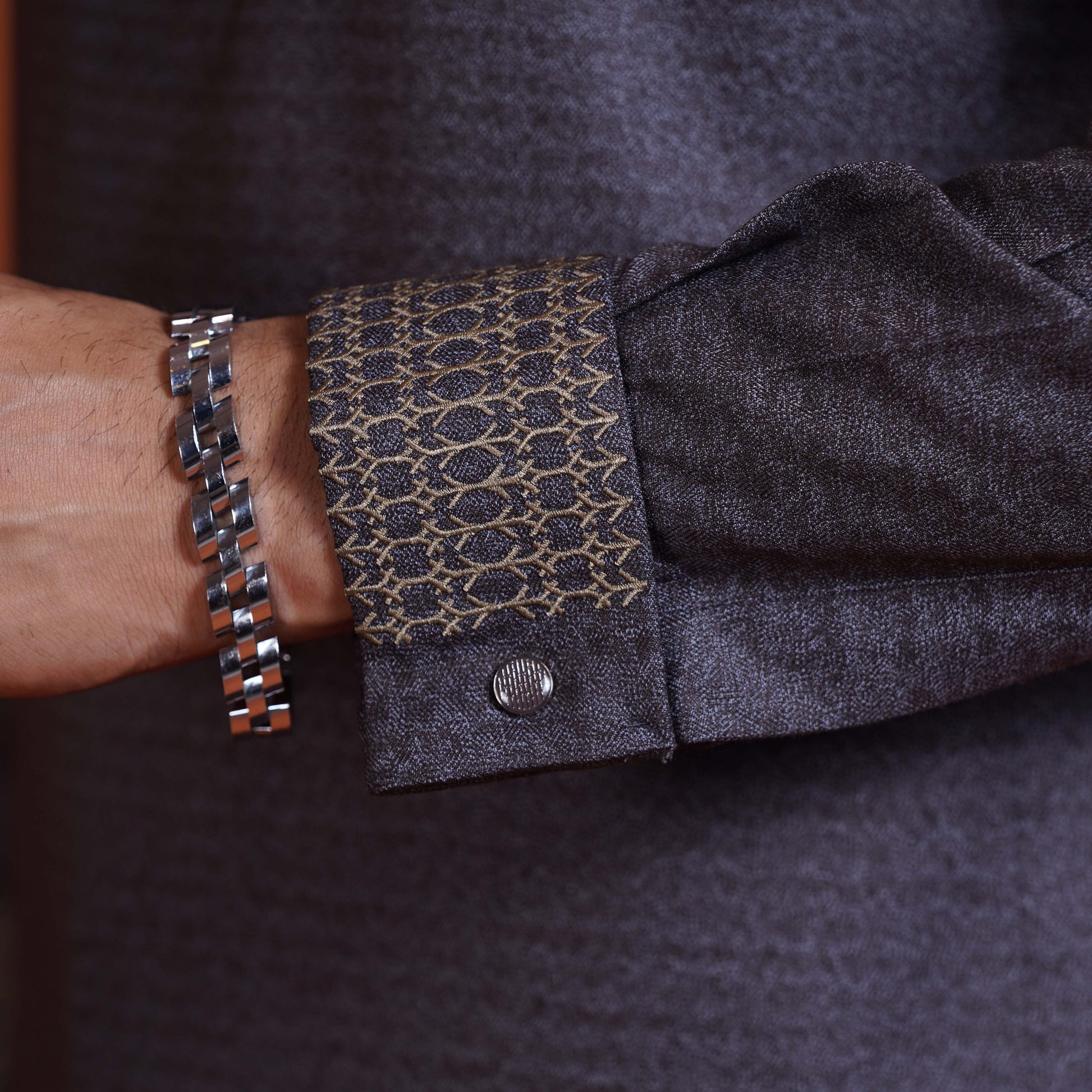 YAMAAN Close-up of a person wearing a dark olive panjabi with patterned cuff and a silver bracelet.