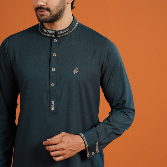 Man wearing a dark green long-sleeve shirt with decorative elements on an orange background