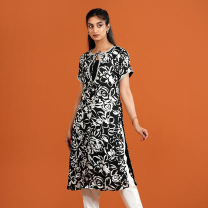 Woman wearing a black and white floral dress on an orange background