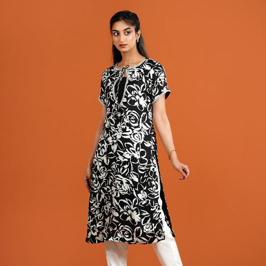 Woman wearing a black and white floral dress on an orange background