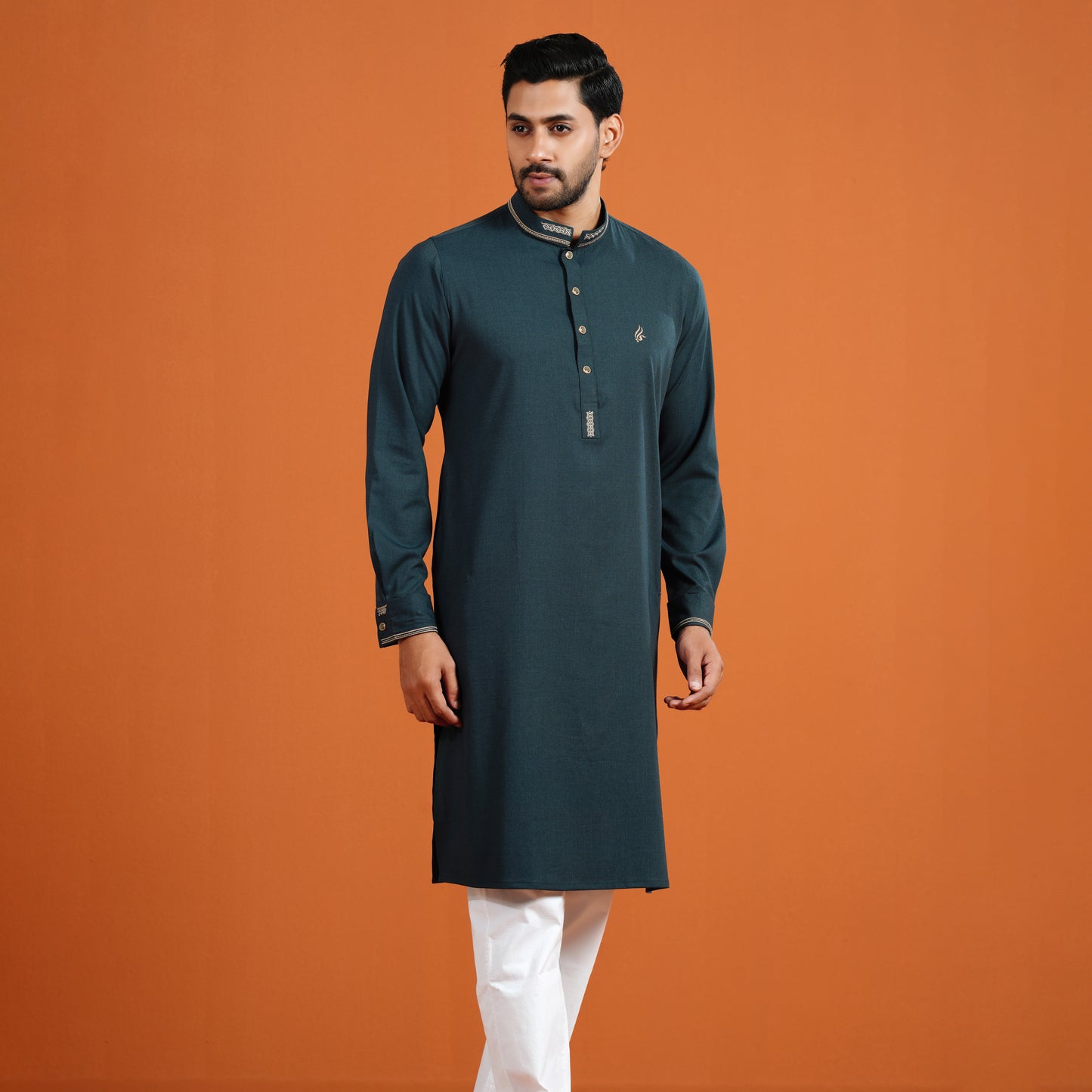 Man wearing a dark green kurta with white pants on an orange background