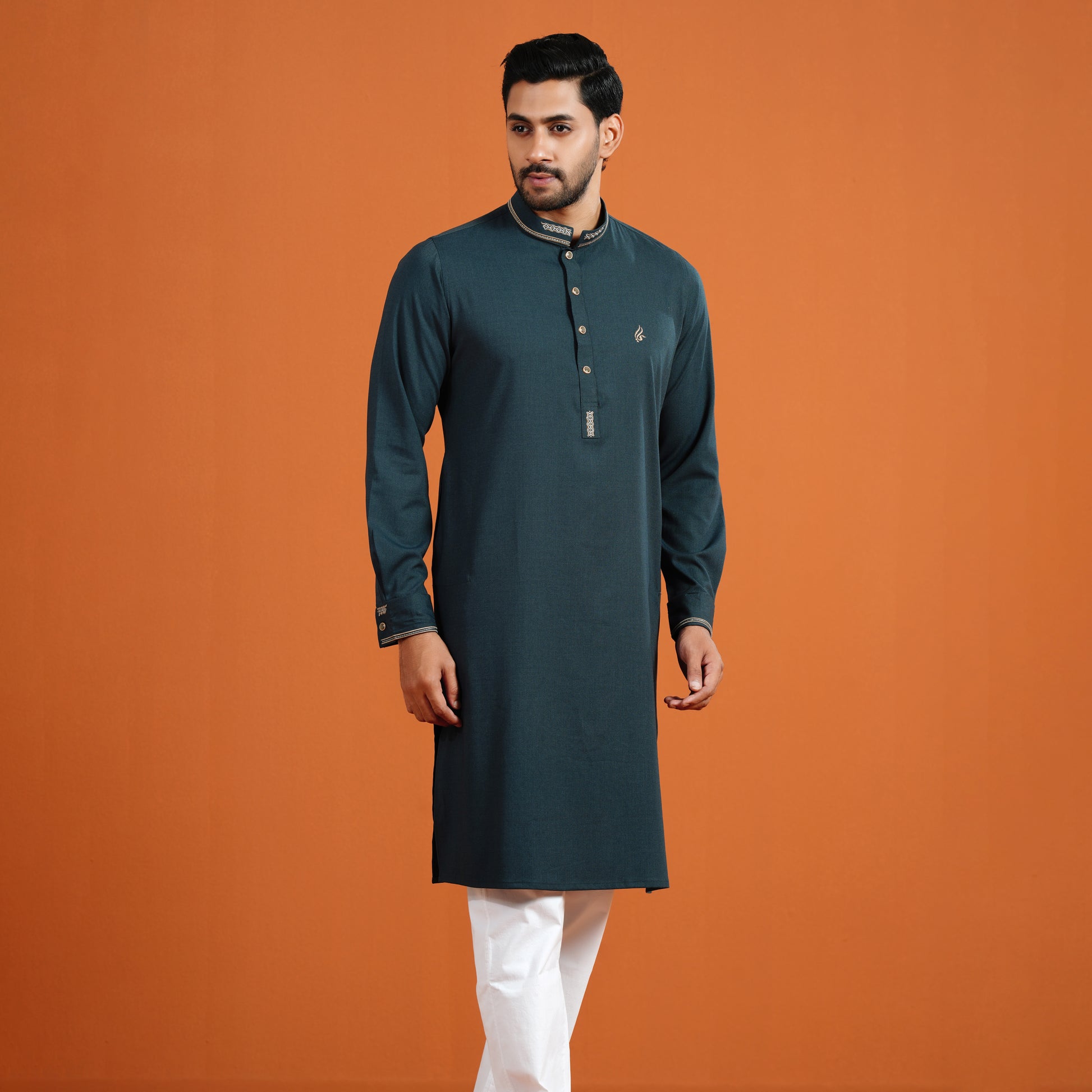 Man wearing a dark green kurta with white pants on an orange background