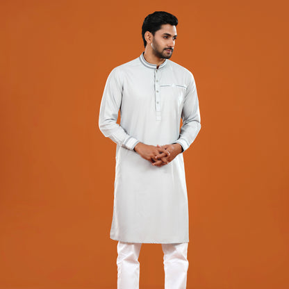 Man wearing a light gray kurta with white pants on an orange background