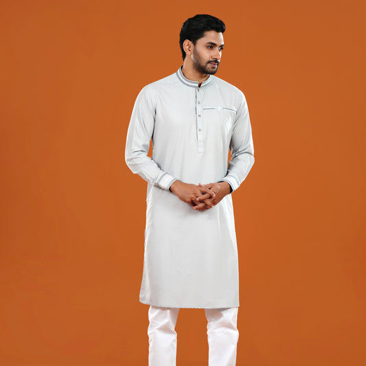 Man wearing a light gray kurta with white pants on an orange background