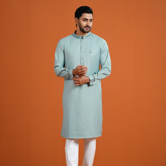 Man wearing a light blue kurta with white pants on an orange background