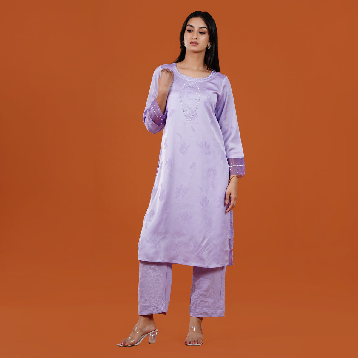 Woman wearing a light purple kurta with pants on an orange background