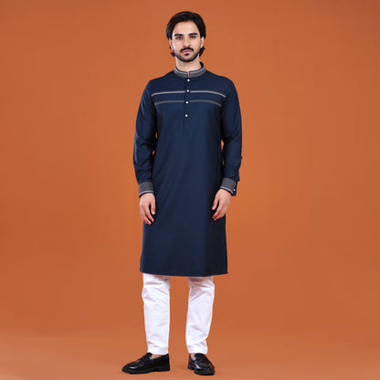 Man wearing a navy kurta with white pants on an orange background