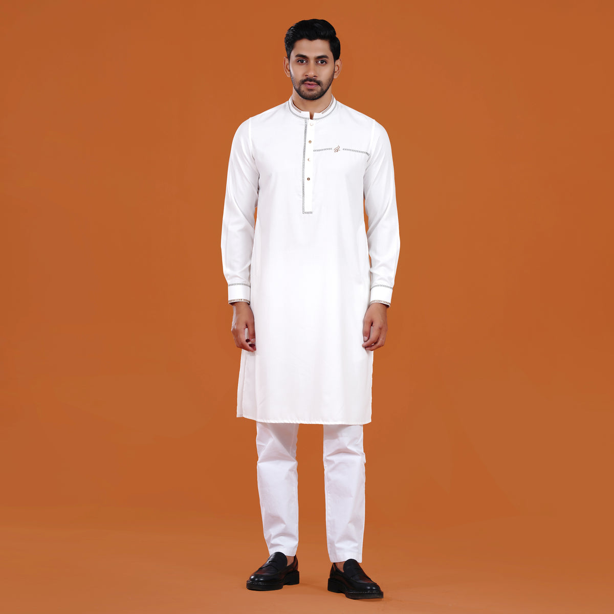 Man wearing a yamaan signature panjabi with black shoes on an orange background