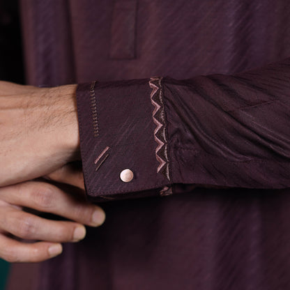 Close-up of a person adjusting the cuff of a Yamaan Signature Panjabi dark purple with intricate detailing.
