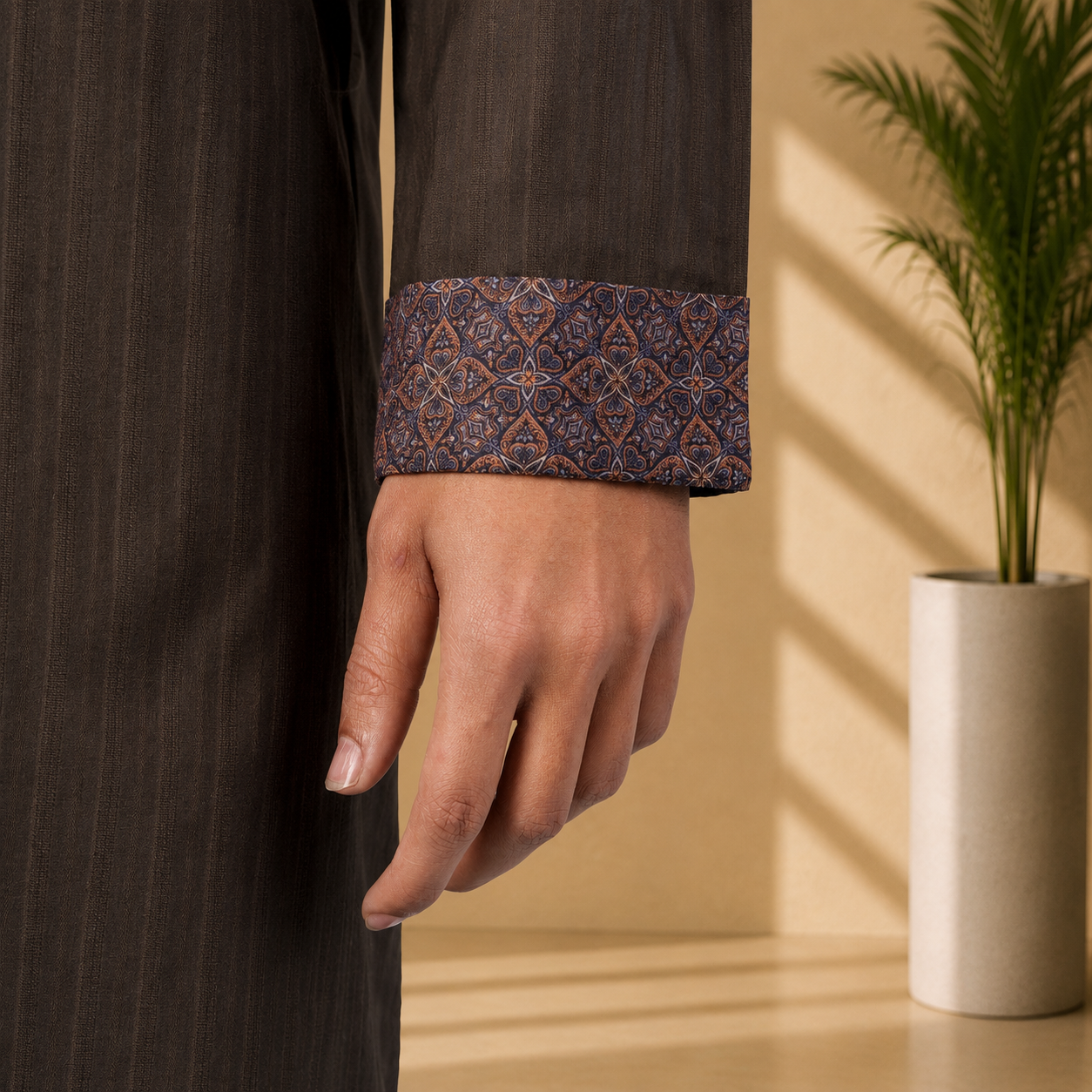 Close-up of a hand wearing a Yamaan royal Panjabi with intricate patterned cuffs, against a neutral background.