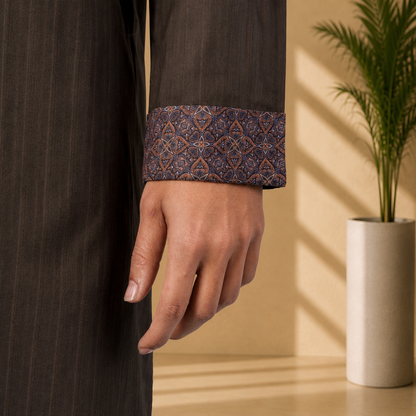 Close-up of a hand wearing a Yamaan royal Panjabi with intricate patterned cuffs, against a neutral background.