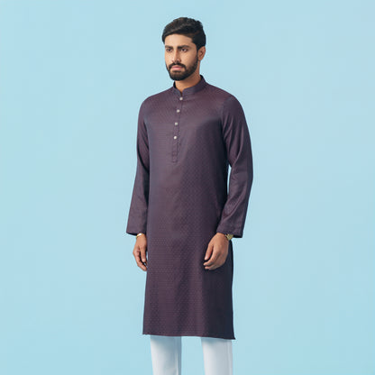 Man wearing a yamaan-royal-panjabi-dark-purple with white pants on a light blue background