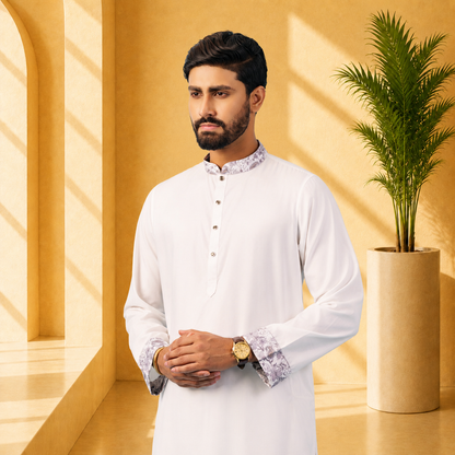 Man in a yamaan royal panjabi traditional outfit standing in a room with a yellow wall and a plant.