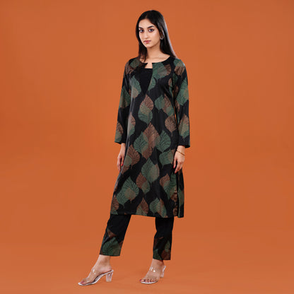 Woman wearing a patterned long coat over a black outfit on an orange background