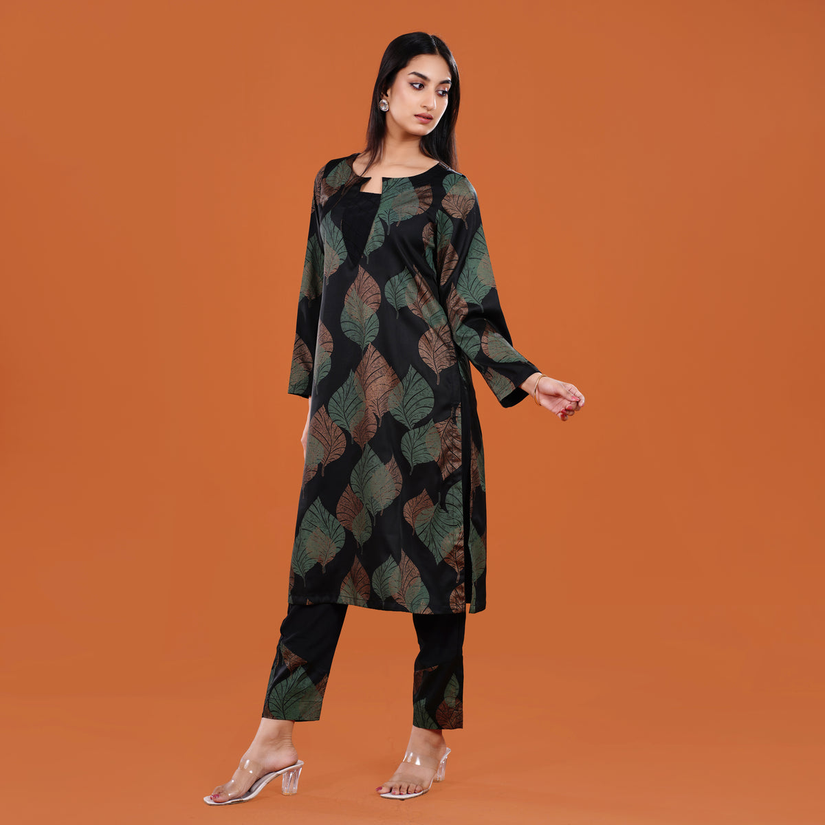 Woman wearing a patterned long coat and pants on an orange background