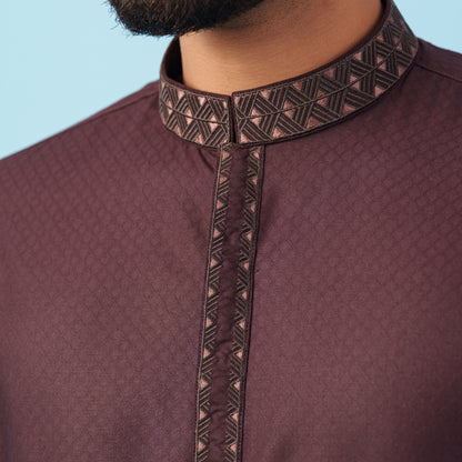 Close-up of a yamaan panjabi with intricate black embroidery on a blue background