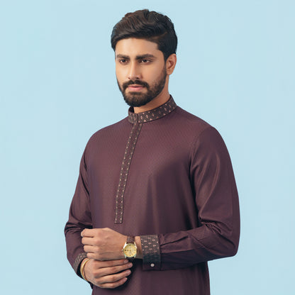 Man wearing a yamaan signature panjabi a traditional outfit with intricate details on a light blue background