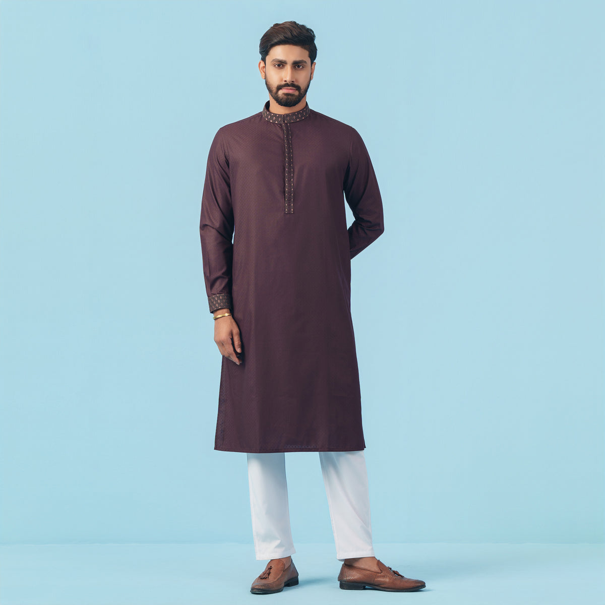 Man wearing a maroon yamaan panjabi with white pants on a light blue background
