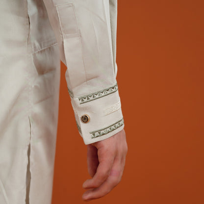 Close-up of a beige sleeve with decorative cuffs against an orange background