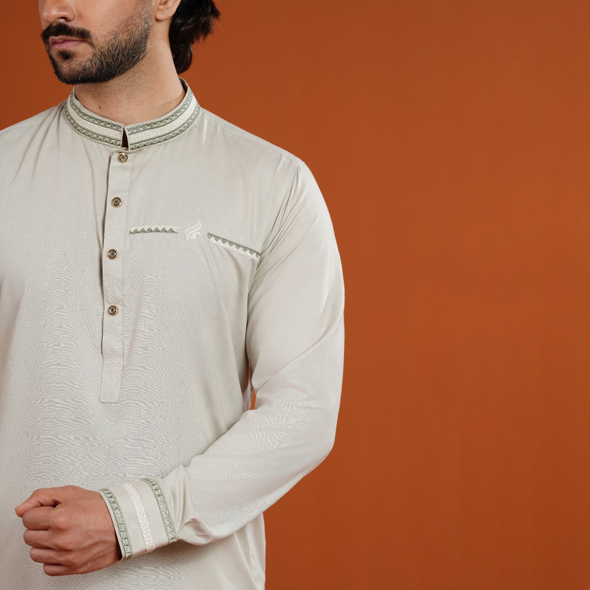 Man wearing a yamaan panjabi with intricate designs on an orange background