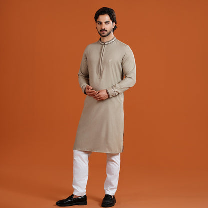 Man wearing a yamaan signature panjabi with white pants on an orange background