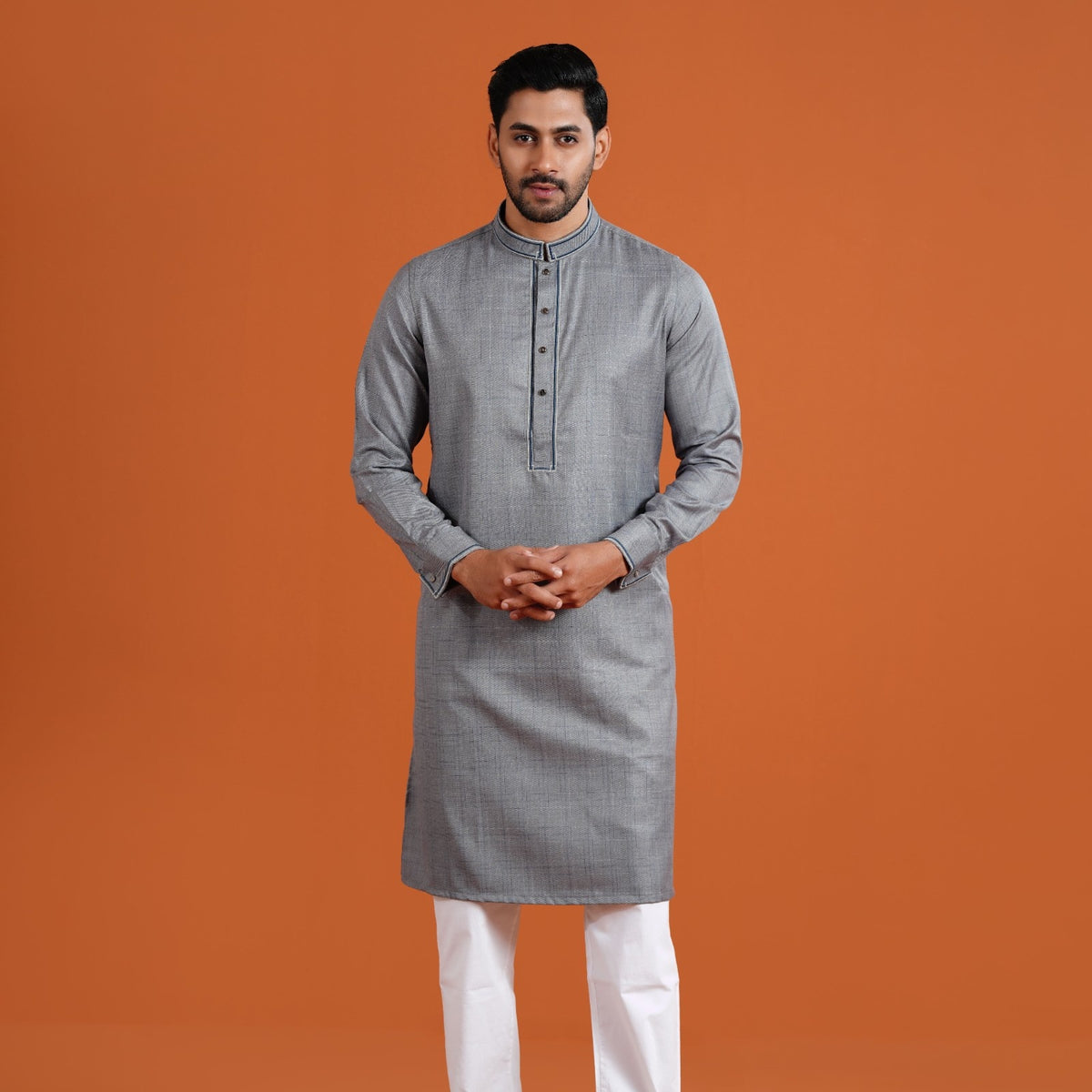 Man wearing a yamaan panjabi with white pants on an orange background